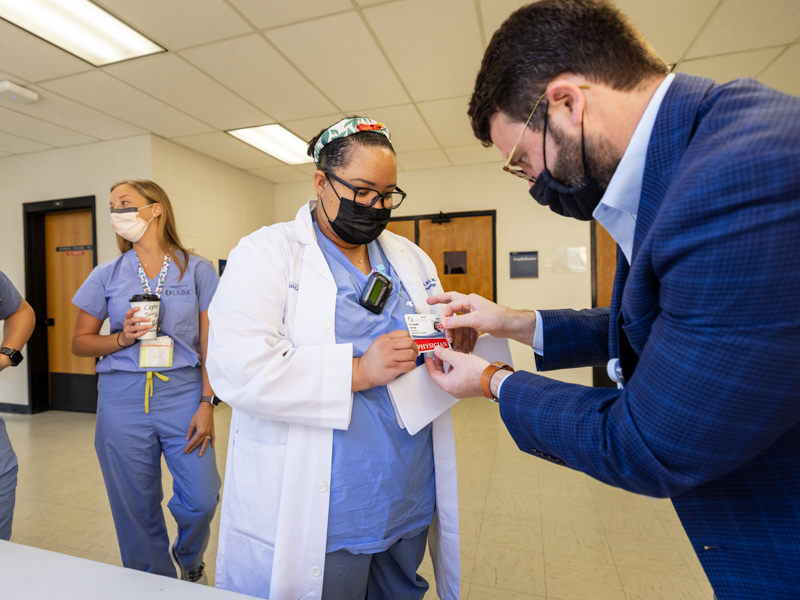 Taylor Sisson, business administrator for the Department of Obstetrics and Gynecology, distributes COVID vaccination stickers to the departments's faculty and residents Wednesday.