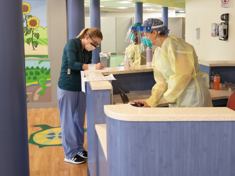 UMMC employee Kelsie Huffman checks in at the symptomatic COVID-19 testing station in the former lobby in the Batson Tower at UMMC. Waiting to help is registered nurse Rachel Hill, right, and certified medical assistant Banca Wallace.