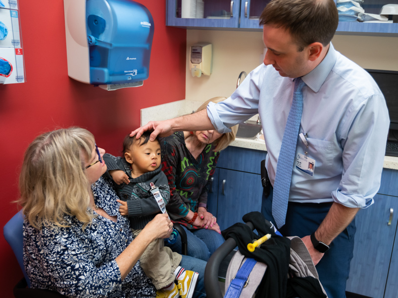 Dr. Ian Hoppe looks over Scotty's face about seven months after initial surgery as Scotty's mom Alli and grandmother Barbara Mellon look on.