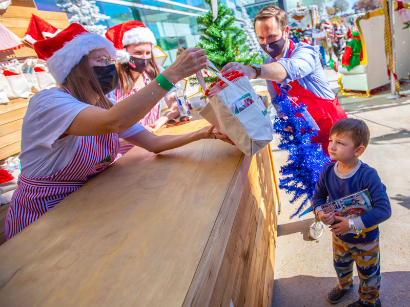 Children's of Mississippi patient Mathis West of Richton gets a bag full of decorations from BankPlus employee Courtney Shaw as UMMC development liaison Ryan Mains helps out with his tree during BankPlus Presents Winter Wonderland.