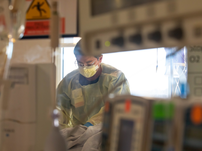 Registered nurse John Yu gives bedside care to a COVID-19 patient in the Medical ICU.