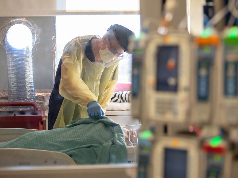 Dr. Ben Brock, an associate professor in the Division of Infectious Diseases, checks COVID-19 patients during rounds on the Medical ICU.