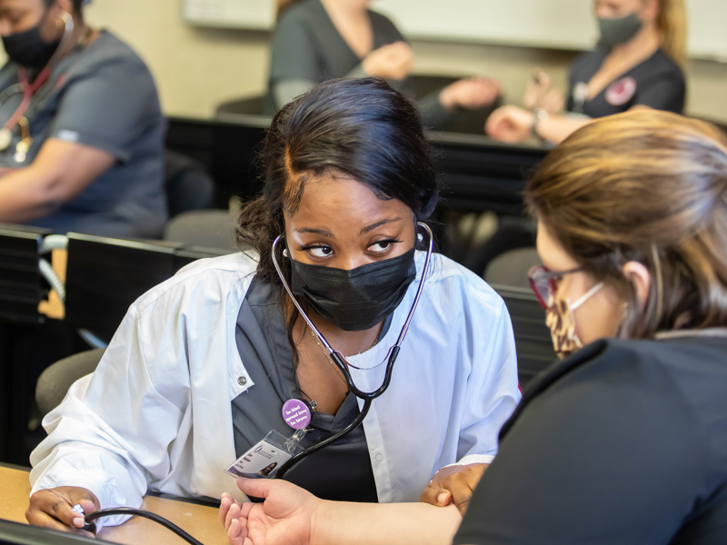 Accelerated BSN student Zoria Nicholson takes the pulse of registered nurse Lauren Cox.