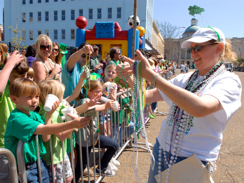 In this file photo taken at Hal's St. Paddy's Parade & Festival, a city sweep volunteer gives Mardi Gras beads to a young Children's of Mississippi supporter.