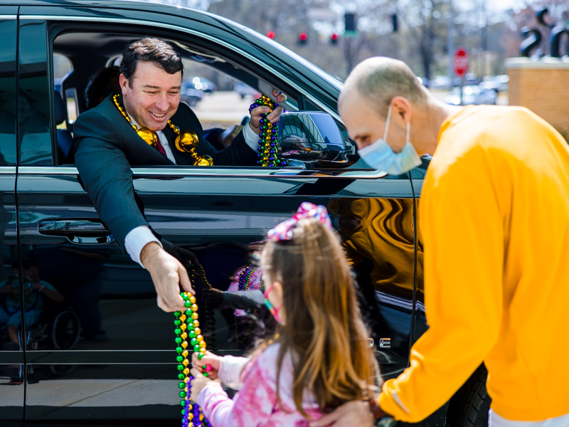 Mississippi Public Safety Commissioner Sean Tindell hands beads to Children's of Mississippi patient Emilia Elkins of Sumrall and her dad, Ash, during a Mardi Gras parade at the children's hospital Thursday.
