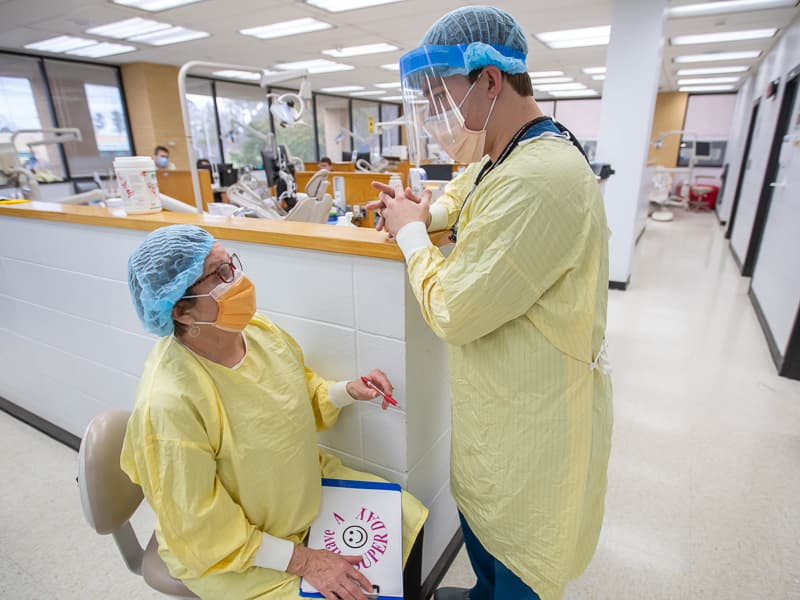 Dental hygiene educator Catherine Gatewood answers questions from fourth-year dental student Chris Fincher as he and other students treat patients with periodontal disease during Dental Mission Week.