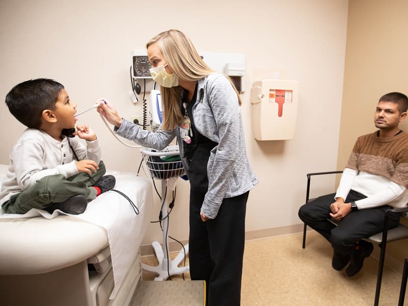 Registered nurse Sarah-Kate Rowan takes the vital signs of patient Jaiden Patel of Brandon as his father, Jagnesh Patel, looks on.