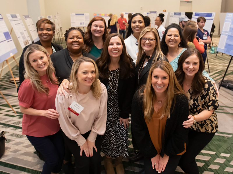 Michelle Palokas, center, associate professor of nursing and director of the Doctor of Nursing Practice program. smiles with DNP students during Nursing Research and Scholarship Day. Palokas was the overall poster award winner.