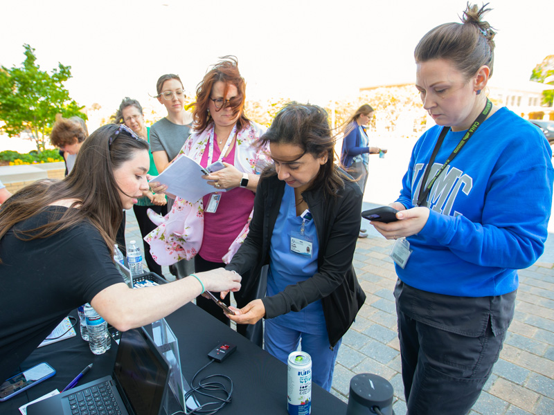 Office of Wellbeing Project Manager Lauren Williams helps Dr. Safia Mohiuddin register for door prizes before UMMC's National Walking Day trek around campus. Melanie Thortis/ UMMC Communications