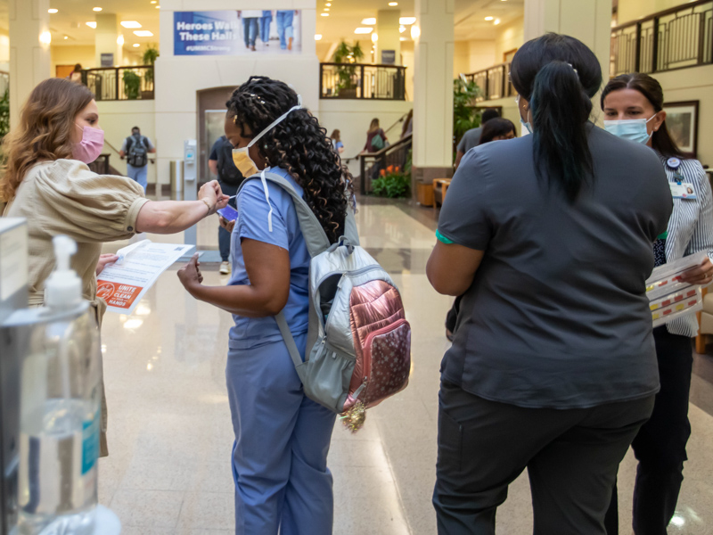 University Hospital surgical tech Yuvonne Kincaid, second from left, gets a sticker from Nursing Administration director Adrienne Murray as Dr. Lisa Didion, associate chief medical officer of UMMC Health System and medical director of care coordination, greets an employee during World Hand Hygiene Day. Melanie Thortis/ UMMC Communications 