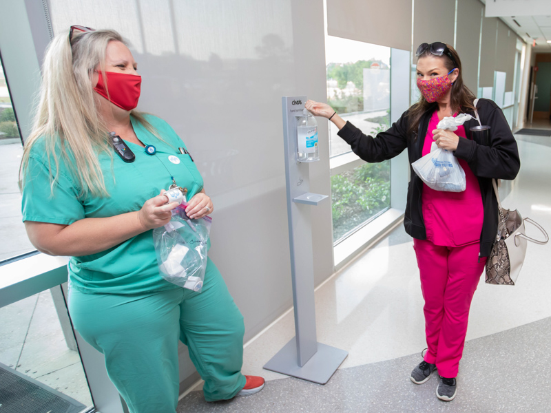 Wiser Hospital for Women and Infants educator and registered nurse Becky Harrison, left, greets Newborn ICU registered nurse Jennifer Nelson as she uses hand sanitizer. Melanie Thortis/ UMMC Communications 