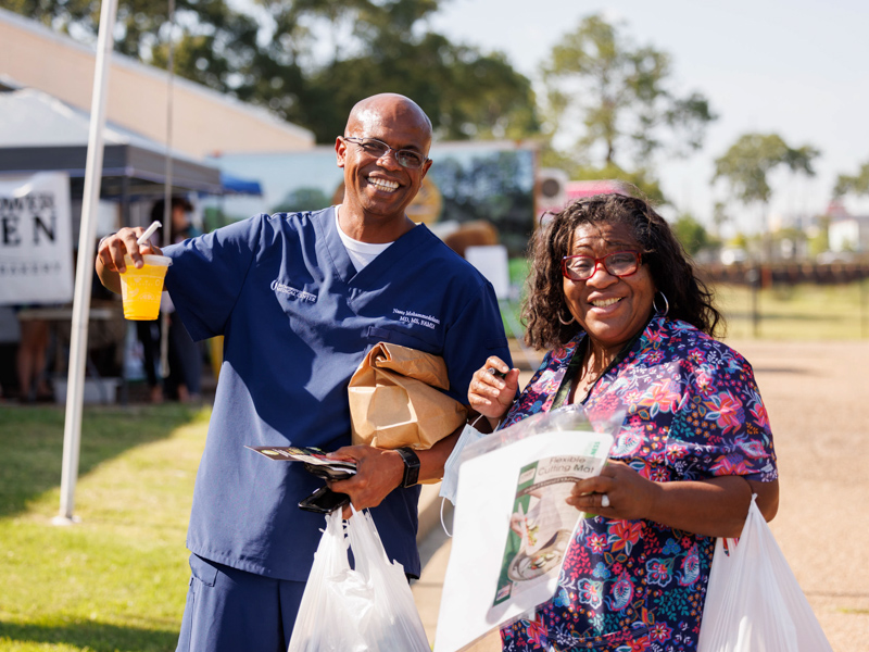 Dr. Naser Mohammedelamien, left, an assistant professor with Preventive Medicine, and Cora Champion, a project manager with the MIND Center, made the most of Thursday afternoon's Farmer's Market behind Backyard Burger with sacks of fresh produce and a cup of juice. The event was sponsored by the UMMC Office of Well-being.