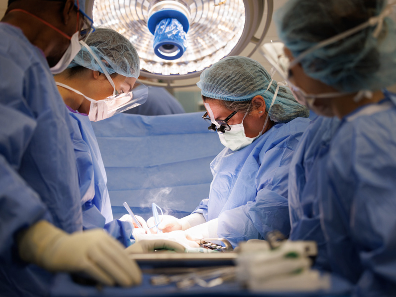 Dr. Felicitas Koller, center, places the kidney of live donor Quinten Hogan into the abdomen of Hogan's mom, Tawanna Davis. She's assisted by a specialized transplant team that includes scrub tech Anthony Poole, left. Joe Ellis/ UMMC Communications 