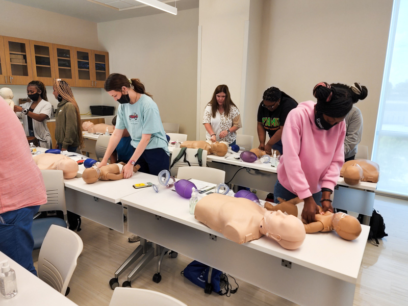 Kardaijah Feazell, a Mount Olive HIgh School senior, right, participates in Basic Life Support Training on an infant-size mannekin during the June session of Mosaic.(Photo courtesy of Dakota Bibbs)