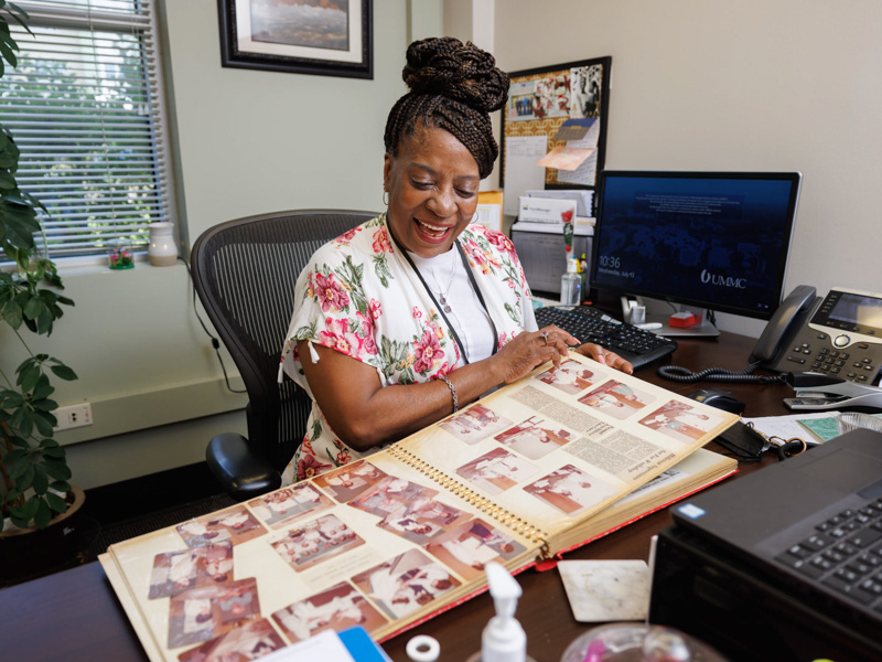 Rose Williams reminisces about her 36.5 years at UMMC while looking through scrapbooks in her office in the School of Health Related Professions. Joe Ellis/ UMMC Communications