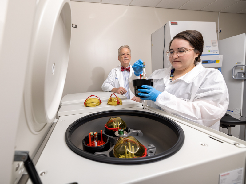 Dr. Gailen Marshall observes as Amy Wigglesworth, nurse navigator for the RECOVER study, centrifuges a participant's blood sample to freeze for future laboratory analysis. Jay Ferchaud/ UMMC Communications 