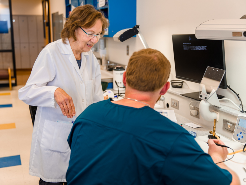 Dr. Karen Carney, a clinical professor in the School of Dentistry, offers encouragement to first-year student Dutton Day during a waxing exercise.