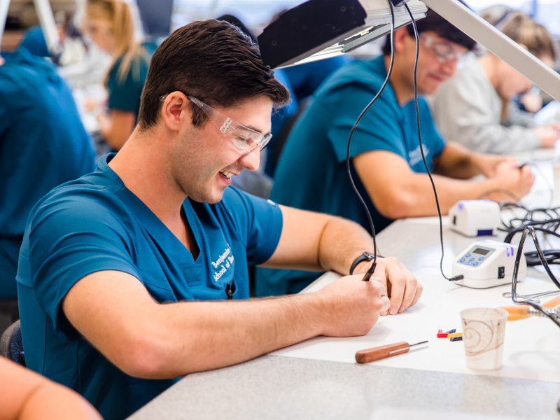 An exercise in creativity for first-year School of Dentistry student Benjamin Draughn requires manipulating heated wax to create a work of art on a popsicle stick.