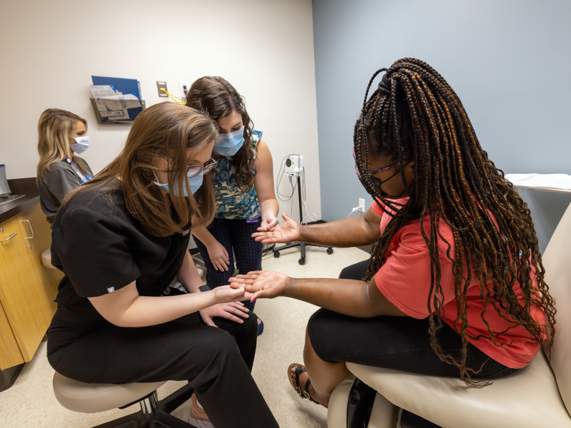 Quanaeqa Hunt, right, of Louisville, describes her skin condition to, from left, dermatology resident Dr. Sarah McClees and medical student Erin Sears at Dr. Adam Byrd's clinic. Hunt, a travel nurse who also works at Winston Medical Center, has worked with Byrd professionally, but is now his patient as well. Jay Ferchaud/ UMMC Communications 