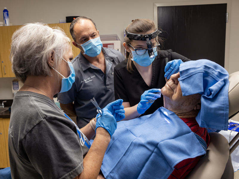 McClees, second from right, a UMMC dermatology resident, performs a procedure on patient Bob McKee, with Vicki Morgan, LPN, left, assisting, as Dr. Adam Byrd observes. Jay Ferchaud/ UMMC Communications