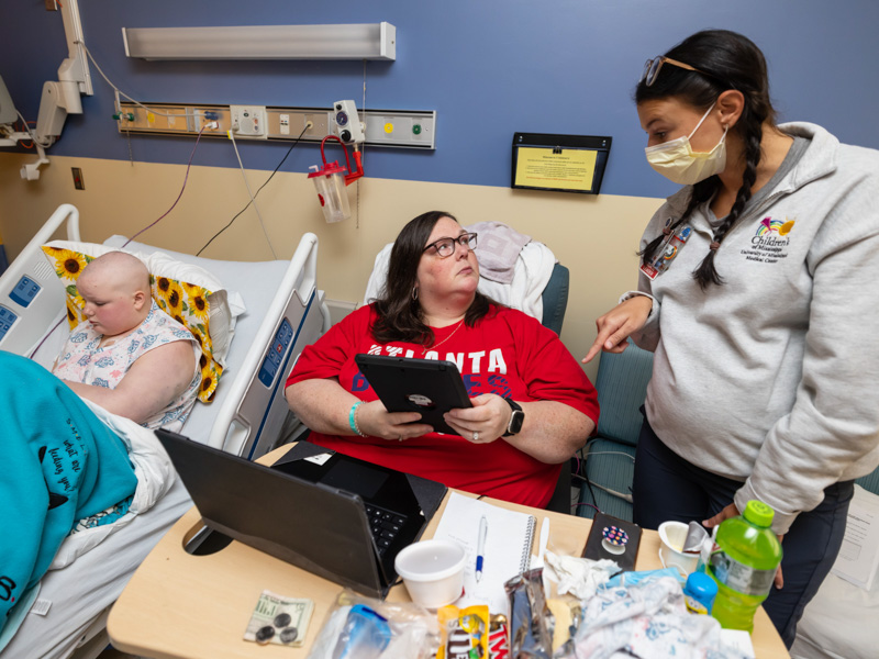 While Children's of Mississippi patient Ella Spinks of Collinsville looks at her phone, nurse educator Baylie Leblanc talks with Ella's mom Keyla Spinks about MyChart Bedside's features. Melanie Thortis/ UMMC Communications