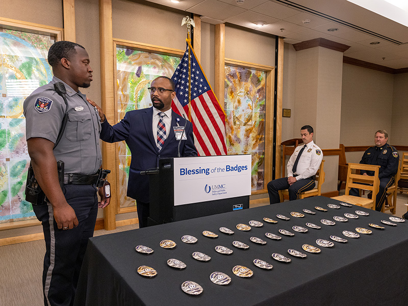 UMMC Chaplain Mark Gilbert, center, blesses the badge of Officer Cameron Smith, who represented the rest of the UMMC Police and Public Safety Department. Jay Ferchaud/ UMMC Communications 