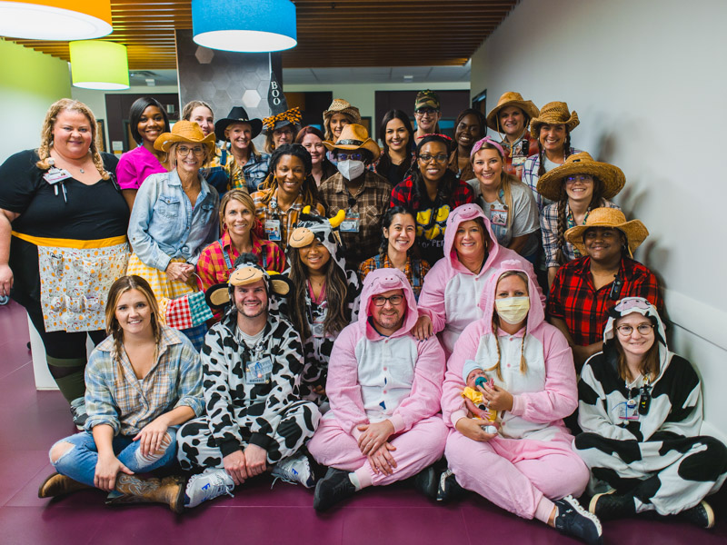The NICU care team plus recent patient Kai Anthony Lee of Gloster smile in their Halloween costumes. Lindsay McMurtray/ UMMC Communications