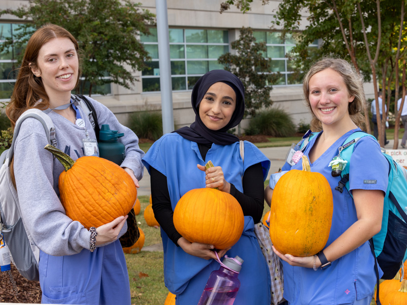 Dental students, from left, Courtney Guest, Kathy Ahmed and Hannah Frazier show their pumpkin choices. Jay Ferchaud/ UMMC Communications 
