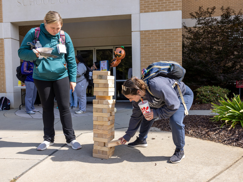 Accelerated nursing student Victoria Jones removes a block from the Jenga stack while classmate Katherine Cole looks on. Jay Ferchaud/ UMMC Communications 