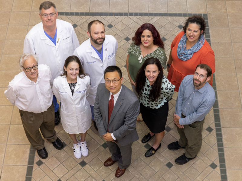 Dr. Lee Zhang, center, joined by co-investigators on the Violence Injury Prevention program, left, and Intimate Partner Violence Initiative, right. Pictured are, front row, from left, Dr. Bill Hillegass, Dr. Laura Vearrier, Zhang, Dr. Erin Dehon and Dr. Andrew Voluse. Back row, from left, are Dr. Carl Mangum, Dr. Matthew Kutcher, Dr. Masoumeh Karimi and Tara Price.