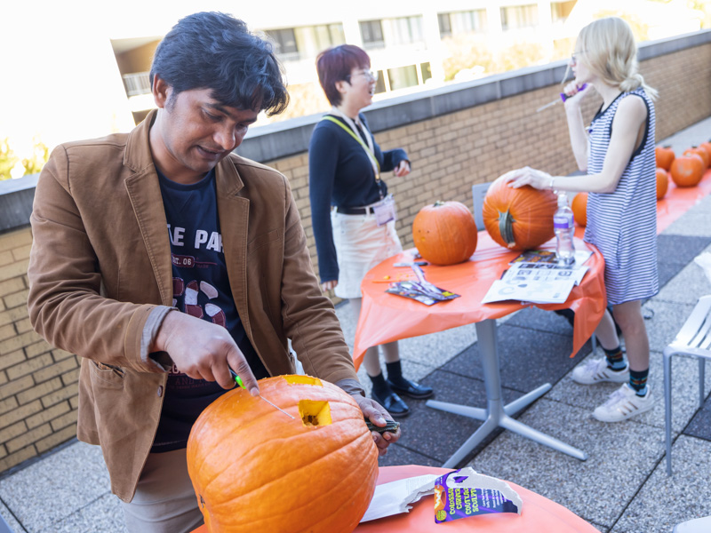School of Population Health Graduate Assistant Md Roungu Ahmmad with the Department of Data Science carves a design on his pumpkin with fellow students. Melanie Thortis/ UMMC Communications 