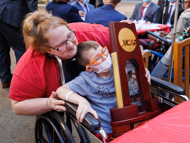 Sarah Sylvester of McLain smiles with son Lukas Baygents while he holds Ole Miss' 2022 College World Series trophy. Joe Ellis/ UMMC Communications