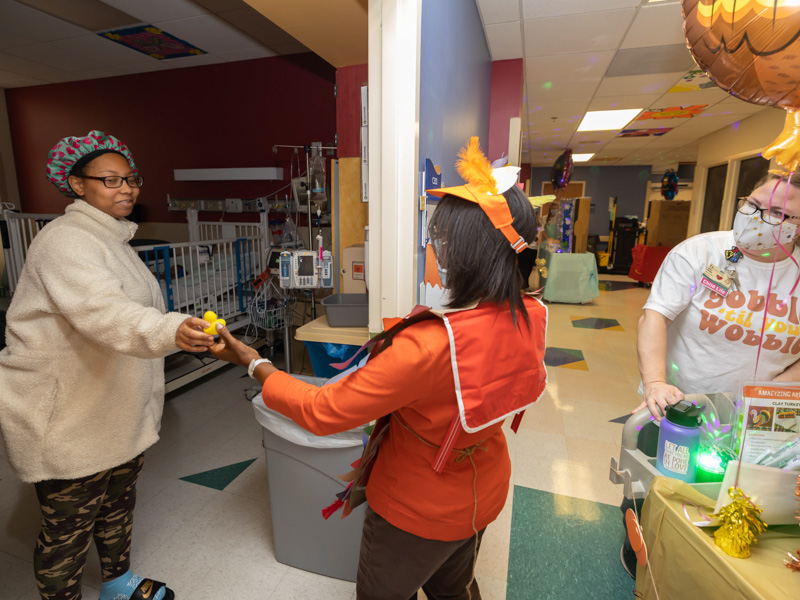 Child life assistant Michelle Chambers, center, gives Nadeia Lee a duck for her child during Children's of Mississippi's annual Thanksgiving Parade. Melanie Thortis/ UMMC Communications
