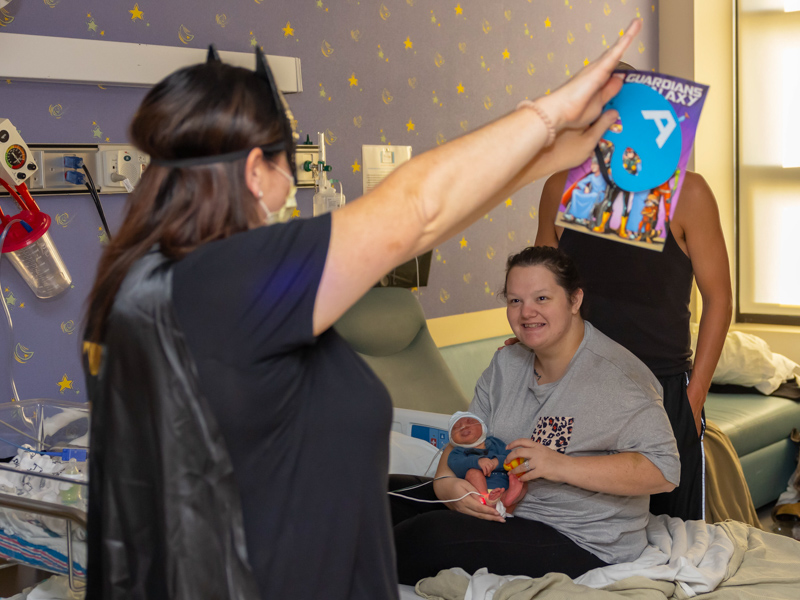 Dressed as a superhero, child life specialist Pepper Weed-Cooper stopped by to visit one of Children's of Mississippi's youngest patients, Waylon Mitchell of Collins, and his mom, Emily Mitchell, during the children's hospital's indoor Thanksgiving Parade. Melanie Thortis/ UMMC Communications