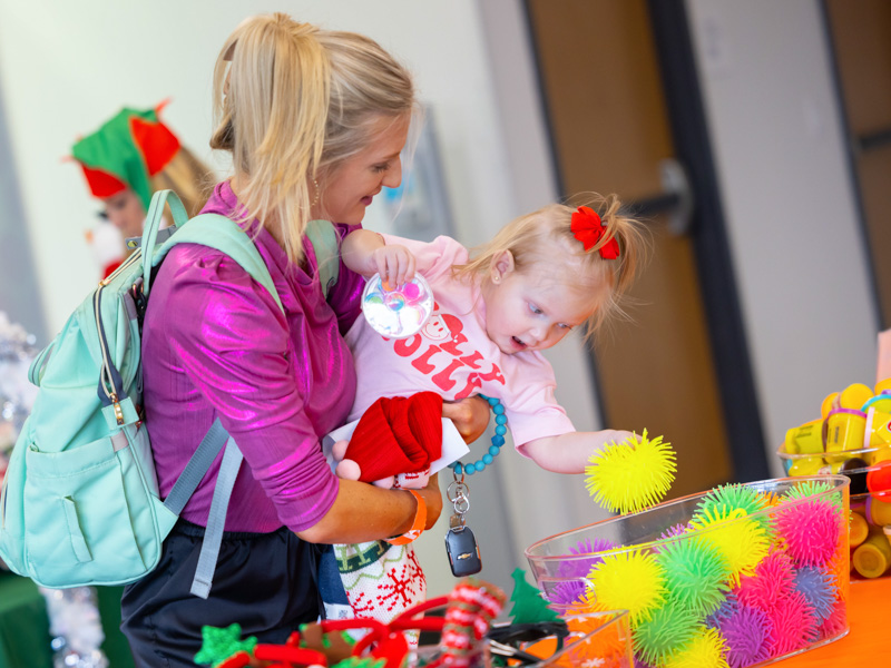 Children's of Mississippi patient Eliza Rideout of Brandon leans in to pick a stocking stuffer with a little help from mom, Lindsey Rideout. Melanie Thortis/ UMMC Communications