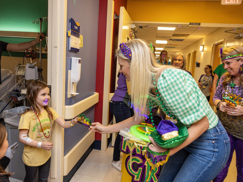 Children's of Mississippi patient Autumn Shirley gets a Mardi Gras tiara from Janna Lampton, a Friends of Children's Hospital board member. Jay Ferchaud/ UMMC Communications 