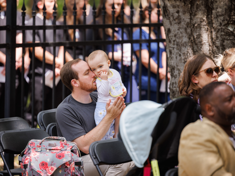 Brynlee Ramer stands in the lap of her father, Cody Ramer, during Wednesday's Anatomical Donor Ceremony. The pair, along with other family members, were in attendance to remember donor Jean Ramer, who was Cody's grandmother and Brynlee's great grandmother.