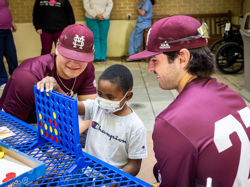 Members of the Mississippi State baseball team watch as Children's of Mississippi patient Jayceston Harris takes a turn in a game of Connect Four. Jay Ferchaud/ UMMC Communications 