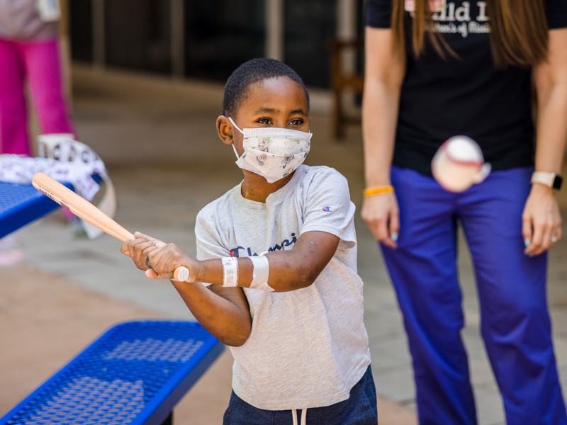 Children's of Mississippi patient Jayceston Harris of Waynesboro swings at a pitch from a Mississippi State University baseball player. Lindsay McMurtray/ UMMC Communications