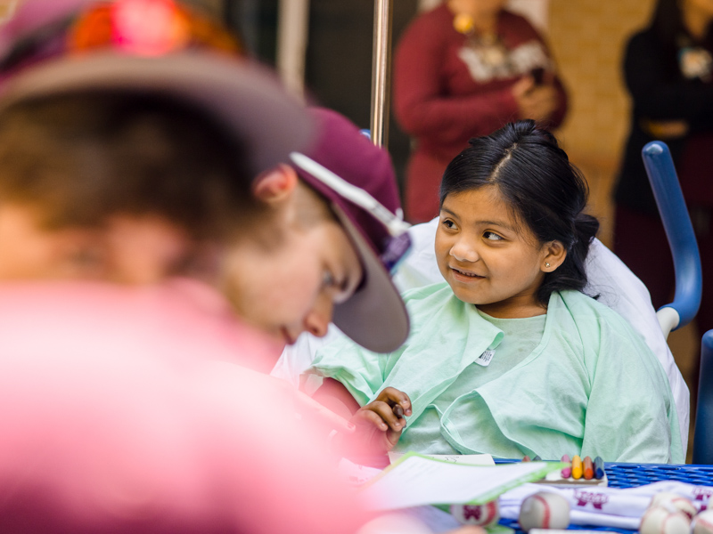 Children's of Mississippi patient Mariola Ramirez of Canton colors with members of the Mississippi State baseball team. Lindsay McMurtray/ UMMC Communications