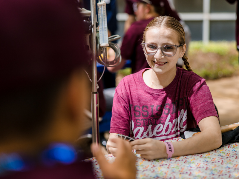 Children's of Mississippi patient Heidi Lewis of McComb smiles during an Uno game with members of Mississippi State's baseball team. Lindsay McMurtray/ UMMC Communications