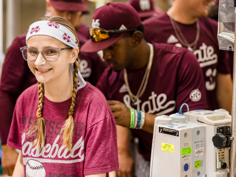 Children's of Mississippi patient Heidi Lewis of McComb smiles as Mississippi State baseball players sign her T-shirt. Lindsay McMurtray/ UMMC Communications