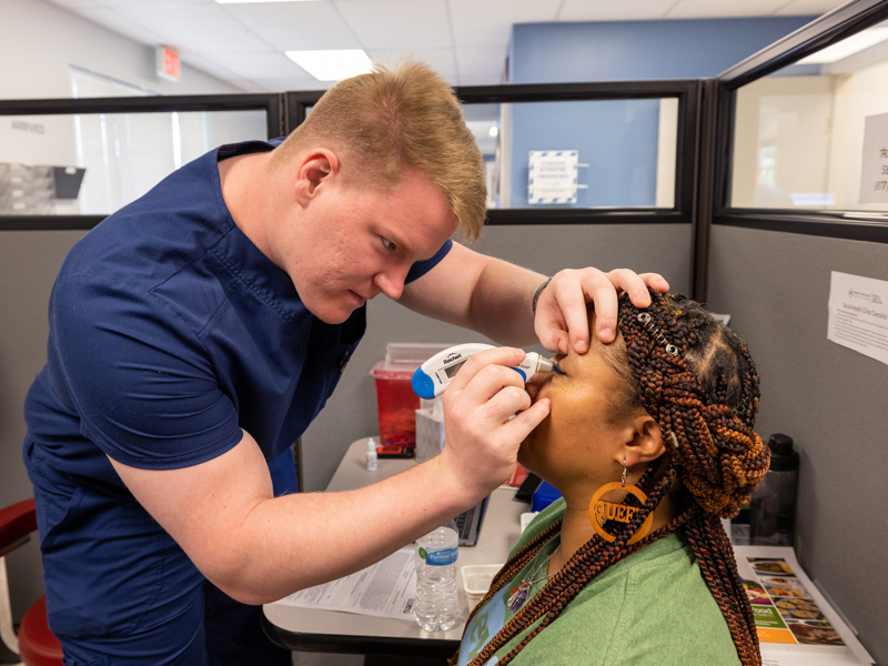 Third-year School of Medicine student Jason Newbaker measures the eye pressure of Jackson Free Clinic vision patient Marilyn Williams of Jackson.