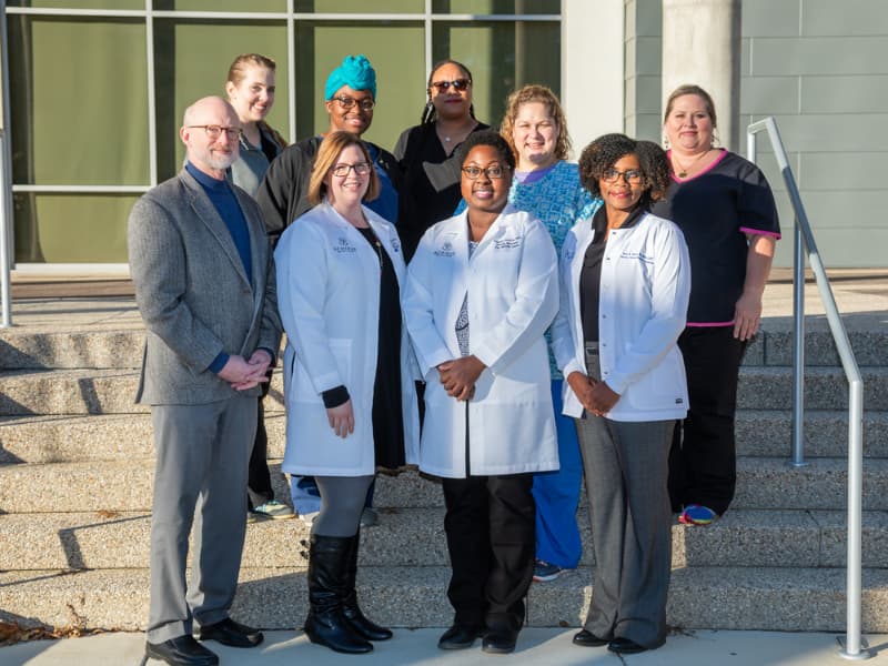 Dr. Thomas Mosley, Robbie and Dudley Hughes MIND Center Chair and Director, The MIND Center (bottom row left), and Dr. Sarah Faucette, associate professor in the Department of Otolaryngology – Head and Neck Surgery and clinical research audiologist with The MIND Center (bottom row, center left), are joined by the ACHIEVE clinical trial research staff in this 2018 file photo. Joe Ellis/ UMMC Communications