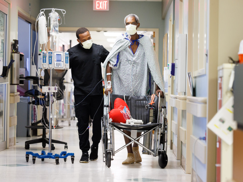 Ricky Mayers of Forest, a heart-kidney transplant patient, takes a walk in the Cardiac Intensive Care Unit, with Eugene Morgan, exercise physiologist in cardiac rehabilitation, closely watching.