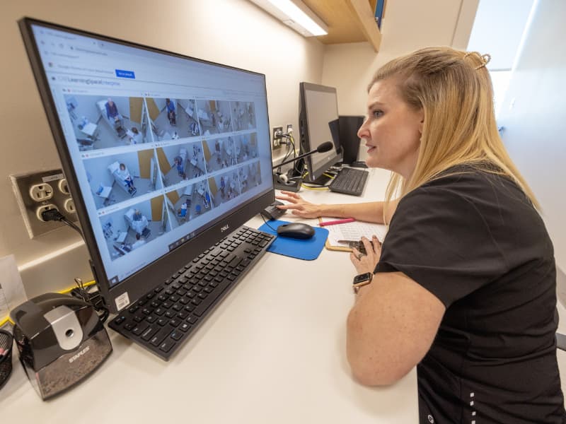 Dr. Alaina Herrington, director of the Judith Gore Gearhart Clinical Skills Center, monitors medical students as they interview Standardized Patients.