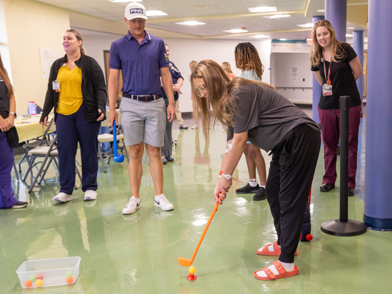 Children's of Mississippi patient Makayla Jones of Moss Point tees up during a golf lesson with Mackenzie Hughes, the 2022 winner of the Sanderson Farms Championship.