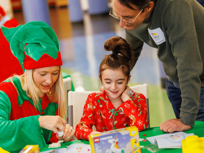 Hope Housel, a senior project assistant with Brasfield & Gorrie, puts together a Lego project with Children's of Mississippi patient Emma Johanson of Brandon. Looking is Emma's dad, Jon Johanson.