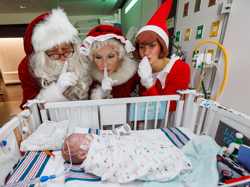 Santa, Mrs. Claus and the Elf on the Shelf are careful not to wake up Children's of Mississippi patient John Chris Bowman of Pelahatchie. Jay Ferchaud/ UMMC Photography 