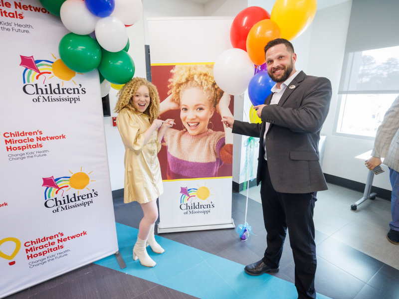 2024 Children's Miracle Network Hospitals Champion Ava Clarke Edney smiles by her banner with Northwest Rankin Principal Lewis Bradford.